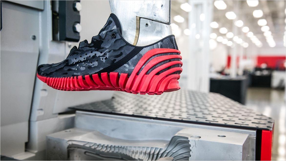 A 3D-printed performance running shoe by Under Armour on a machine in a factory.