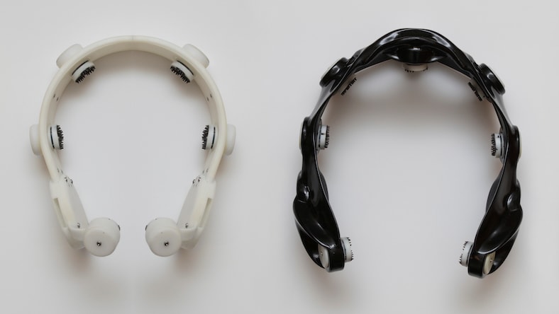 Two EEG brain-computer interface headsets show the design progression from the original model (white, left) to the final generative model (black, right).