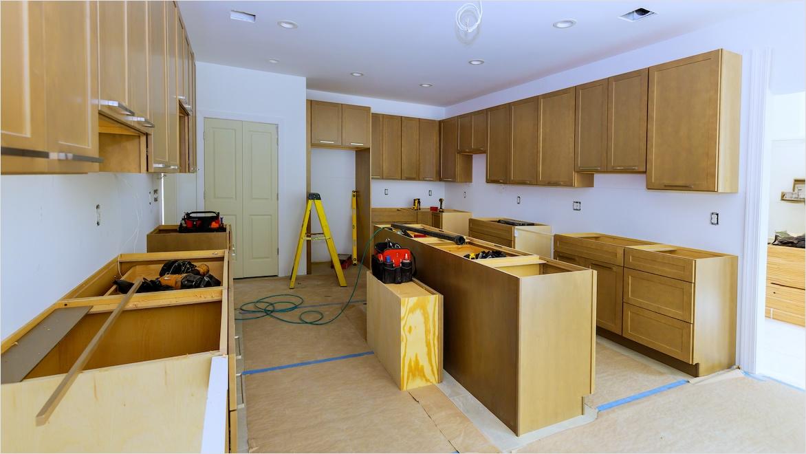 A kitchen under construction has installed cabinets but no countertops or appliances.