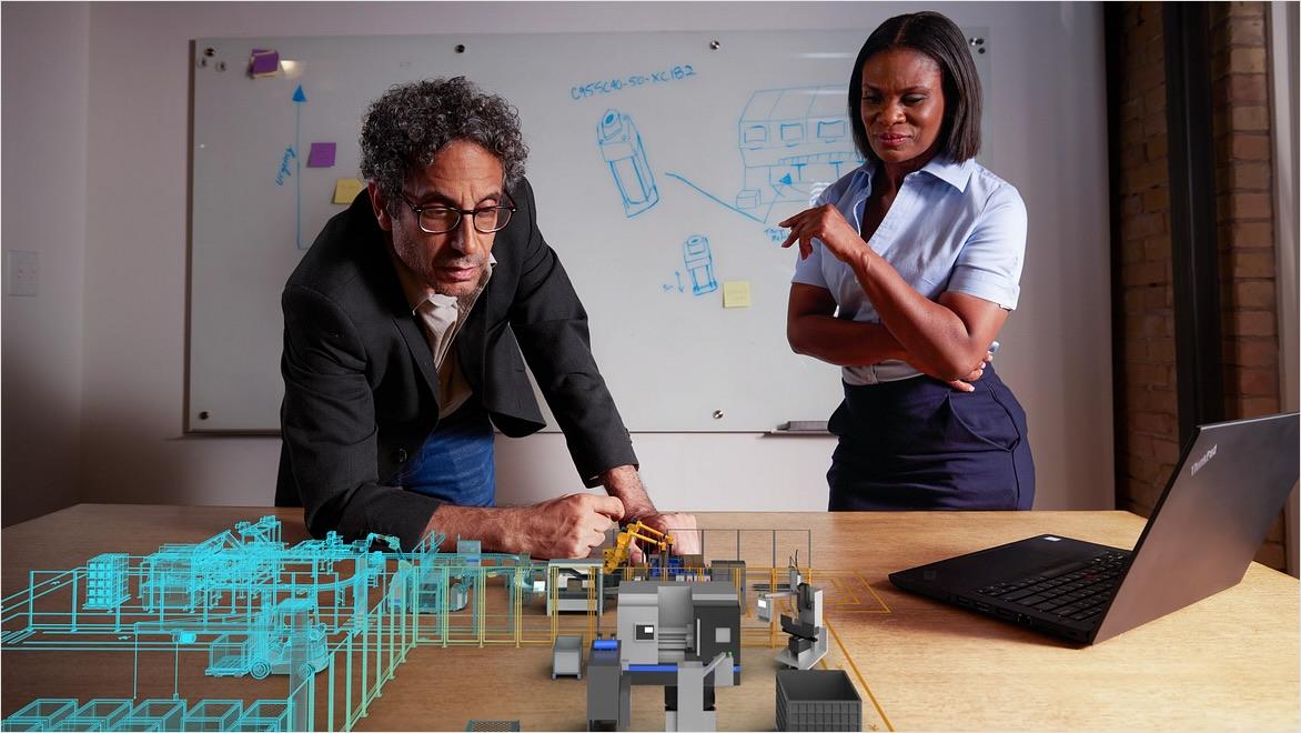 A man and a woman look at an overlay depicting the digital model of a factory.