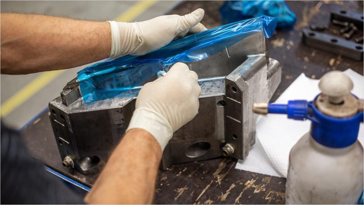 Gloved hands remove a hard tooling part from a mold.