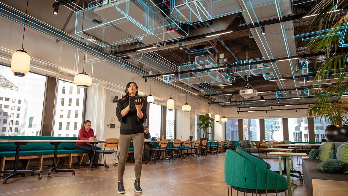 An engineer consults a tablet; in the background, a virtual overlay outlines HVAC equipment.