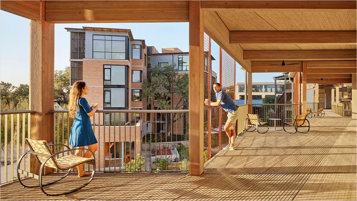 A man and woman standing on a large mass timber deck.