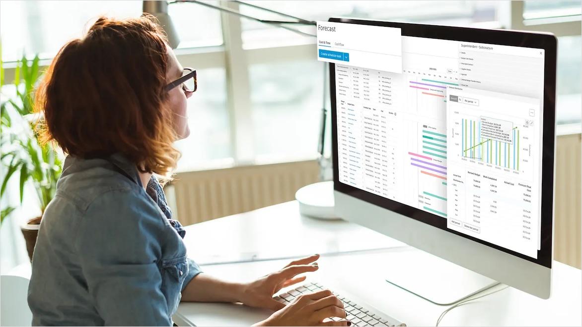 A woman works at a desktop computer that is overlaid with screen captures of several project dashboards.