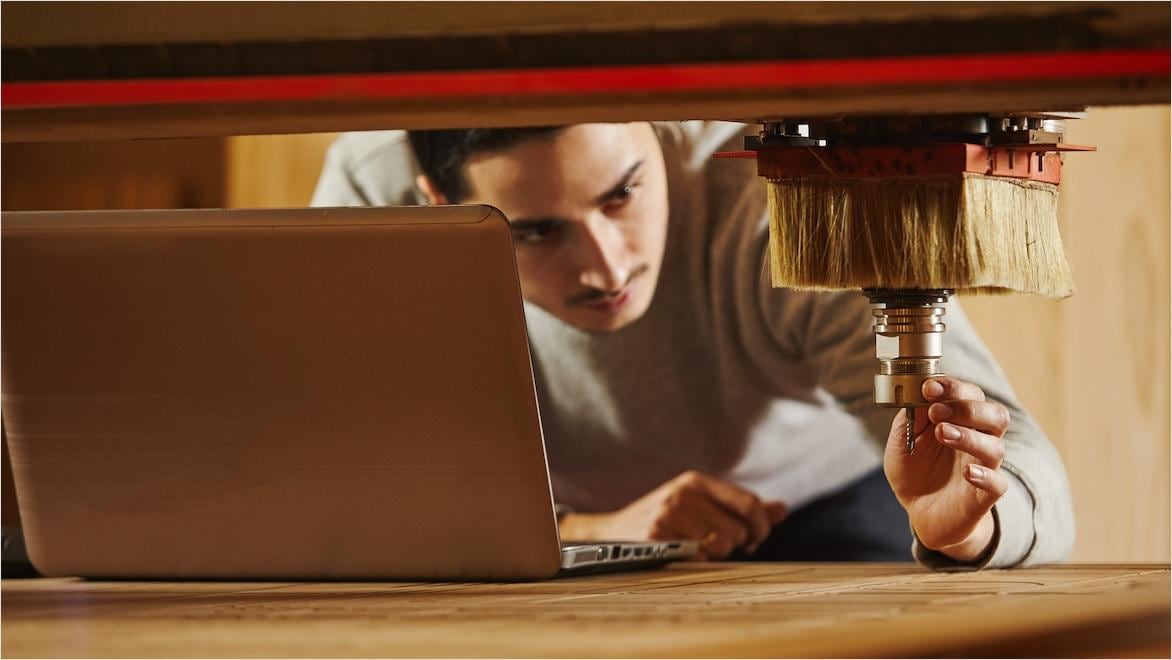 A man sets the cutter on a CNC machine for cutting wood.