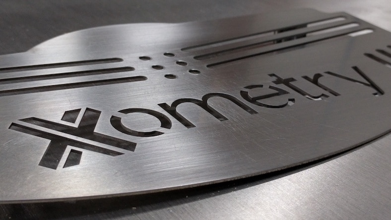 A piece of metal with the word 'Xometry' carved into it.