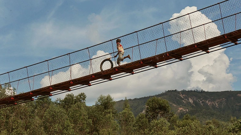 A boy runs across a footbridge.