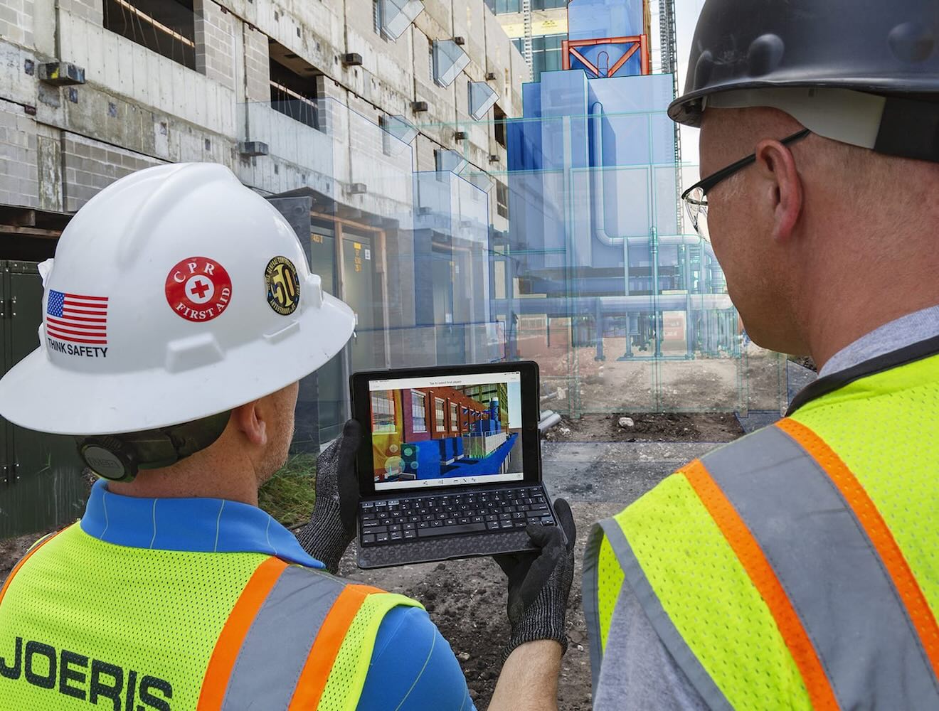 Two men in safety gear on a construction site view construction data on a tablet, with an overlay suggesting augmented reality.