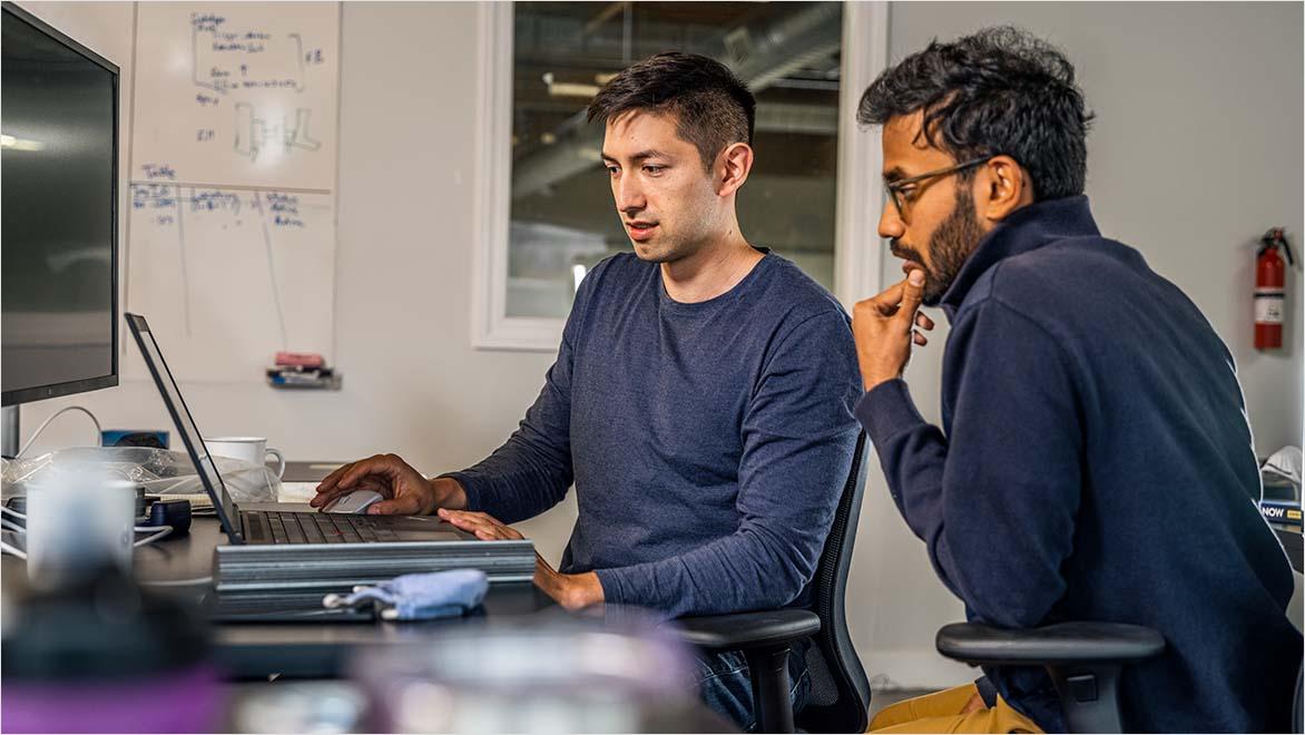 Two men look at computer screen.
