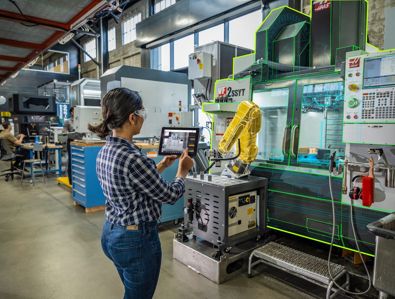 A woman uses a tablet while working in a CNC shop.