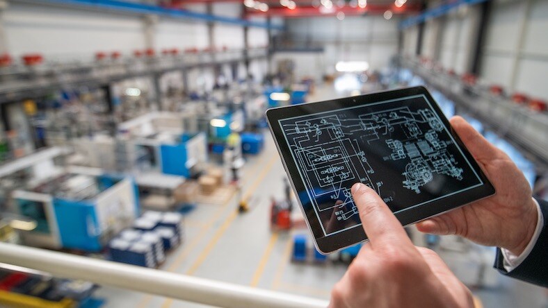 Hand on tablet above factory floor