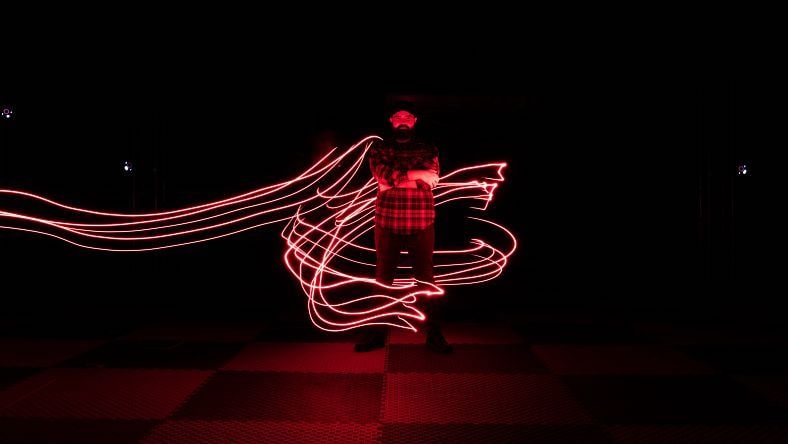 Lights swirl around a man in a dark room.