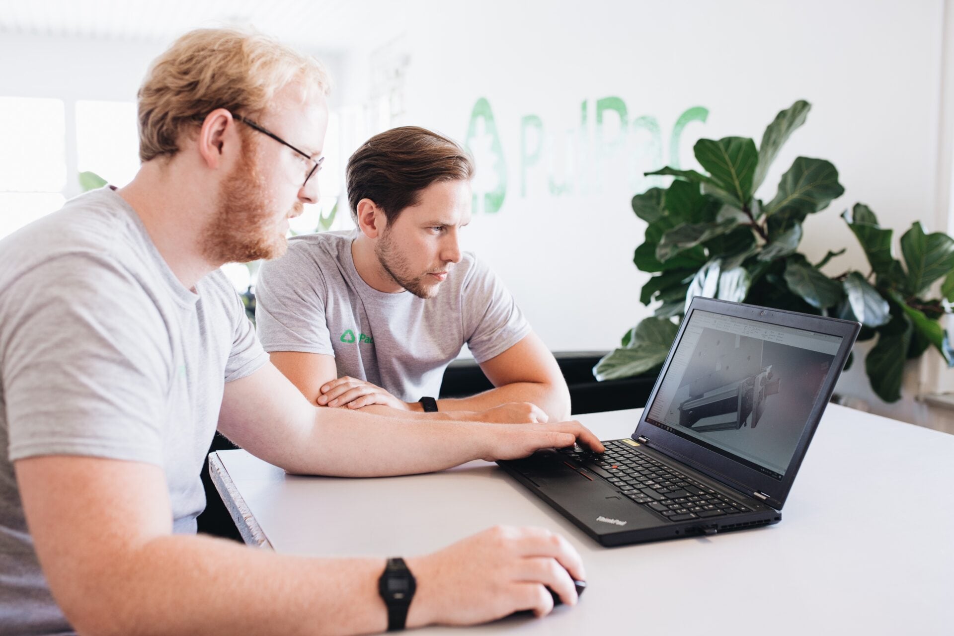 Two people looking at a CAD model on a laptop