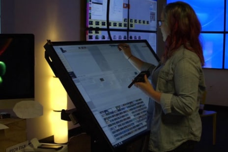 Woman standing and interacting with a large screen that has ShotGrid software open