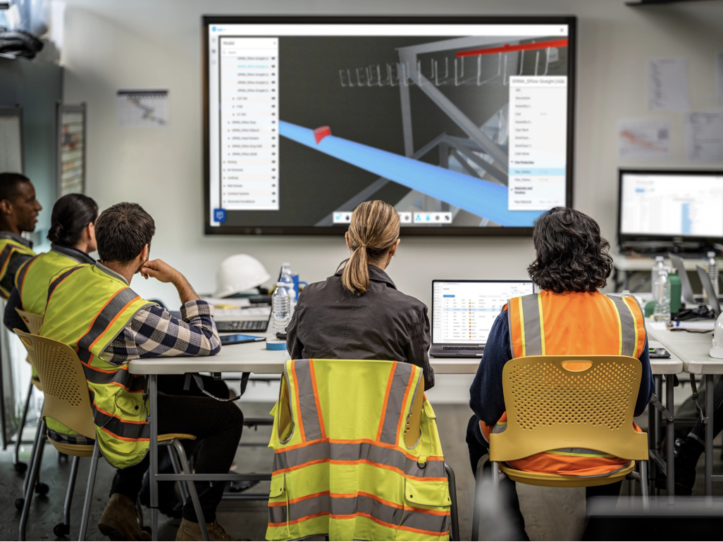 Engineers in meeting room viewing a Revit building model on a large screen