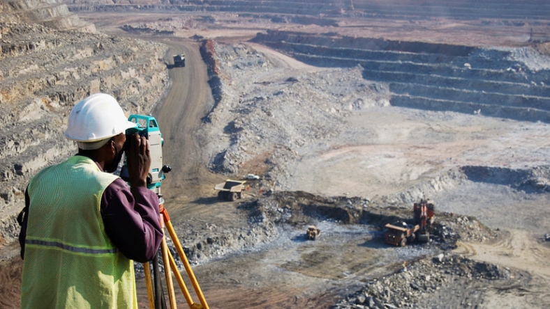 Surveyor looking through instrument at an open-pit copper mine