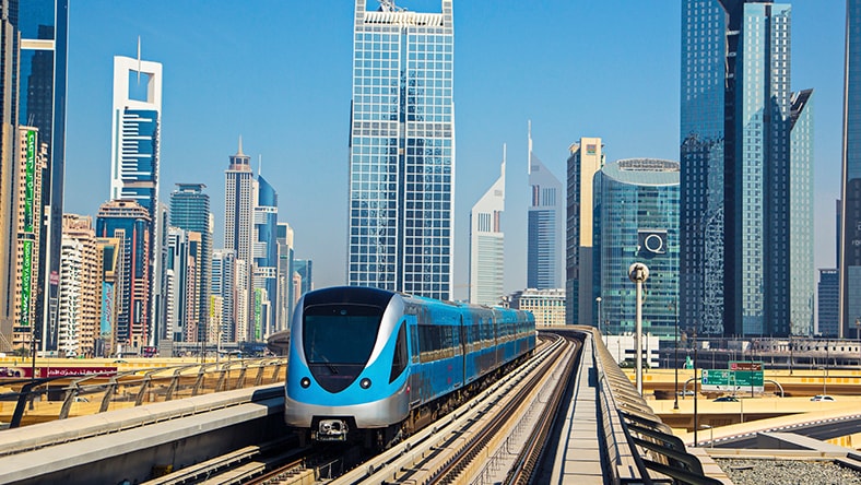 Passenger train approaching with cityscape in background
