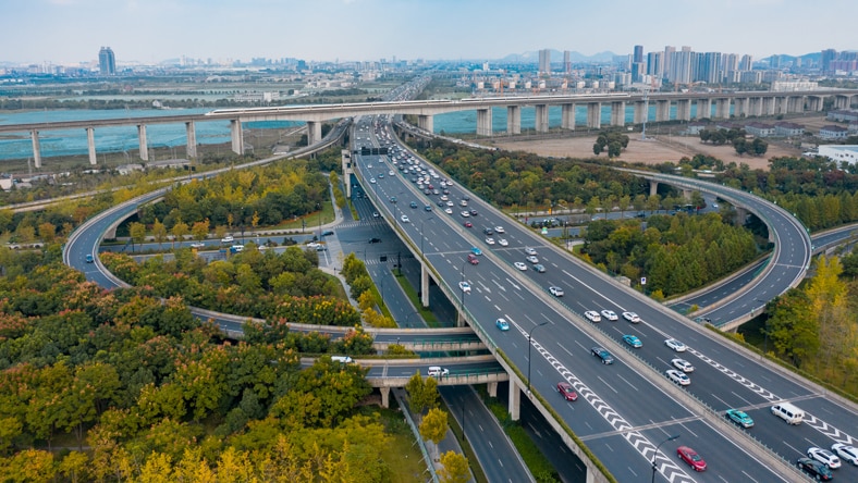 Aerial view of highway interchange with river and city in background