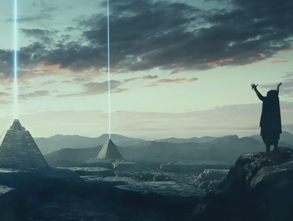 Person standing on hill pointing towards pryamids