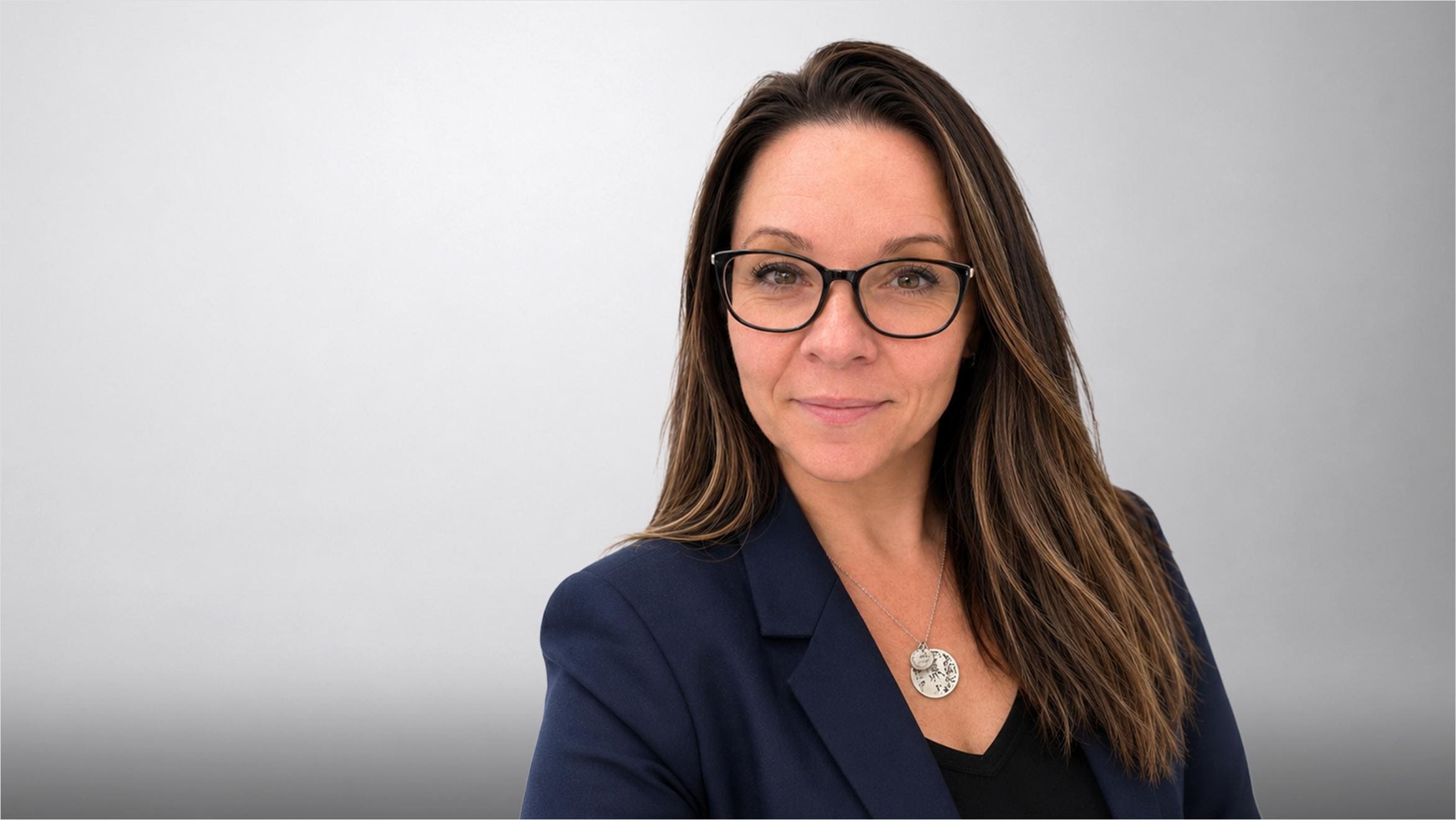 Portrait of a woman in glasses wearing a dark blazer with a brooch.