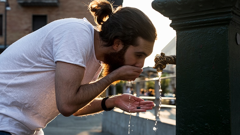 A man drinking water from the tap