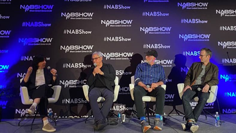 Four people on stage talking.