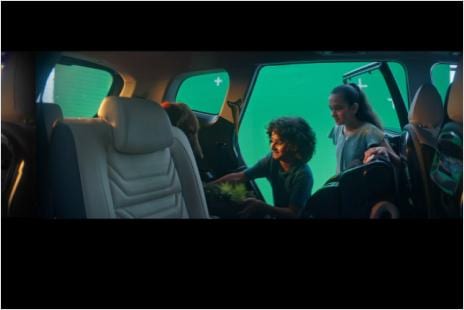 2 Kinder öffnen eine Autotür, hinter ihnen ein Greenscreen