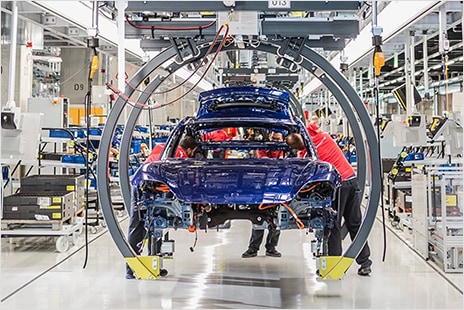 A vehicle being assembled by robots in a Porsche facility