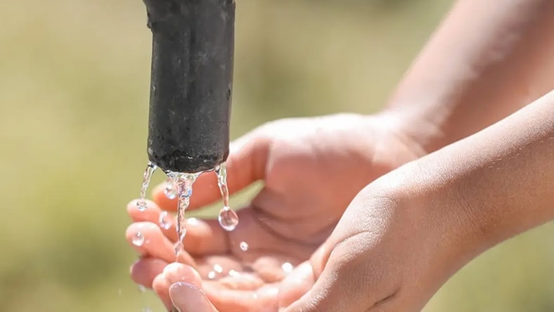 hands cupped beneath a tap catching clean water