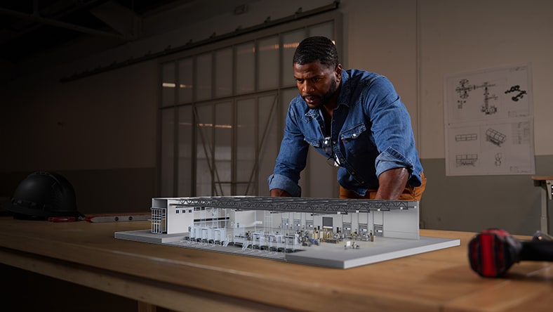 Engineer in office looking at factory model on table