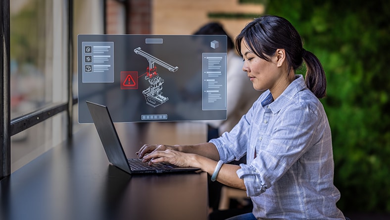 Engineer working on laptop with quality management workflow displaying on screen 