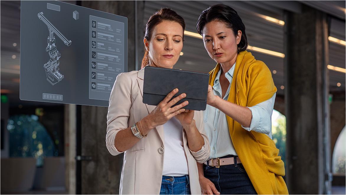 Two women looking at tablet with screen displayed behind them showing bill of materials