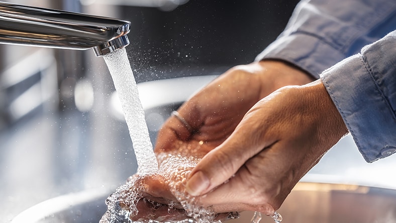Person washing hands under a tap