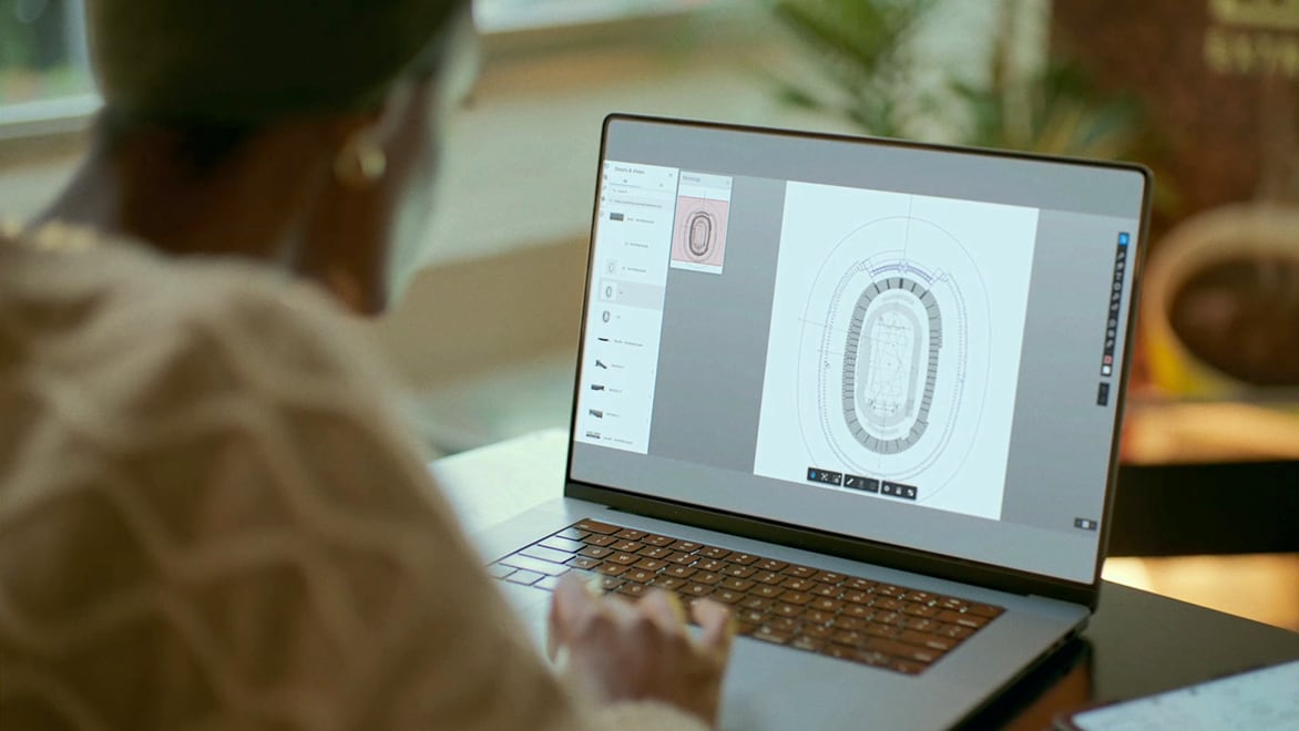 A designer looks at a stadium schematic on their laptop computer