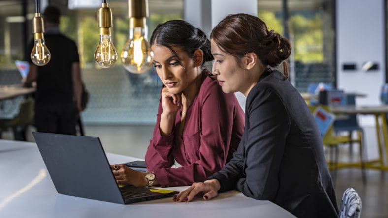 two women side by side looking at laptop