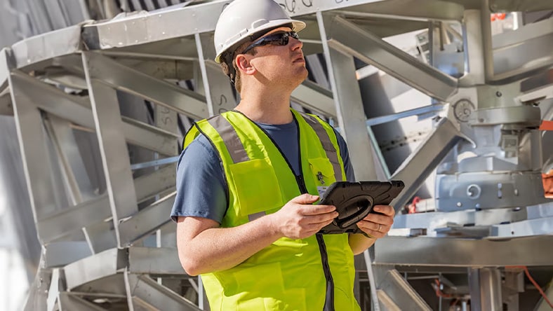Illustration of a prime contractor leading a team on a construction site, with one team member reviewing plans and another discussing logistics, surrounded by building materials and equipment.