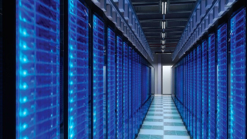 An interior of a data center showing rows of blue-hued data servers.
