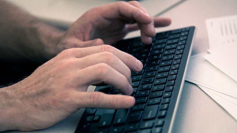 A closeup view of two hands on a computer keyboard.