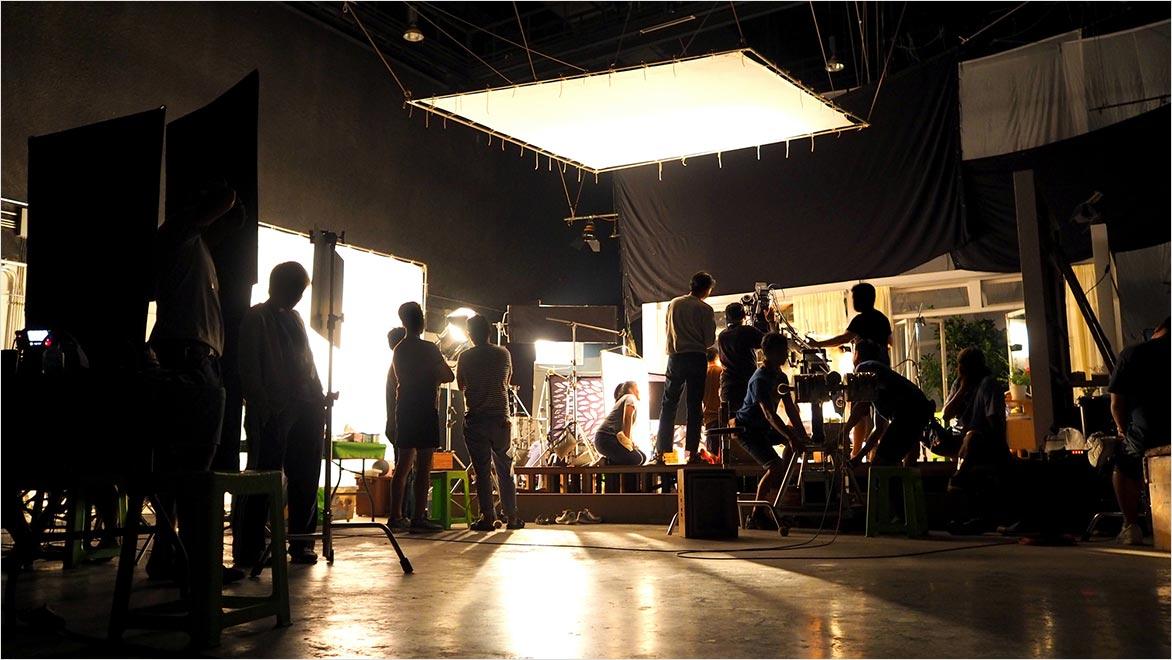 Behind the scenes or the making of film video production and movie crew team working in silhouette of camera and equipment set in studio.