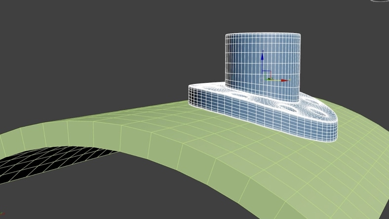Rectangular blocky object in 3ds Max with a cylindrical tower being conformed onto a curved, hilly green surface