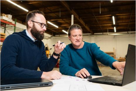 two workers pointing at a laptop