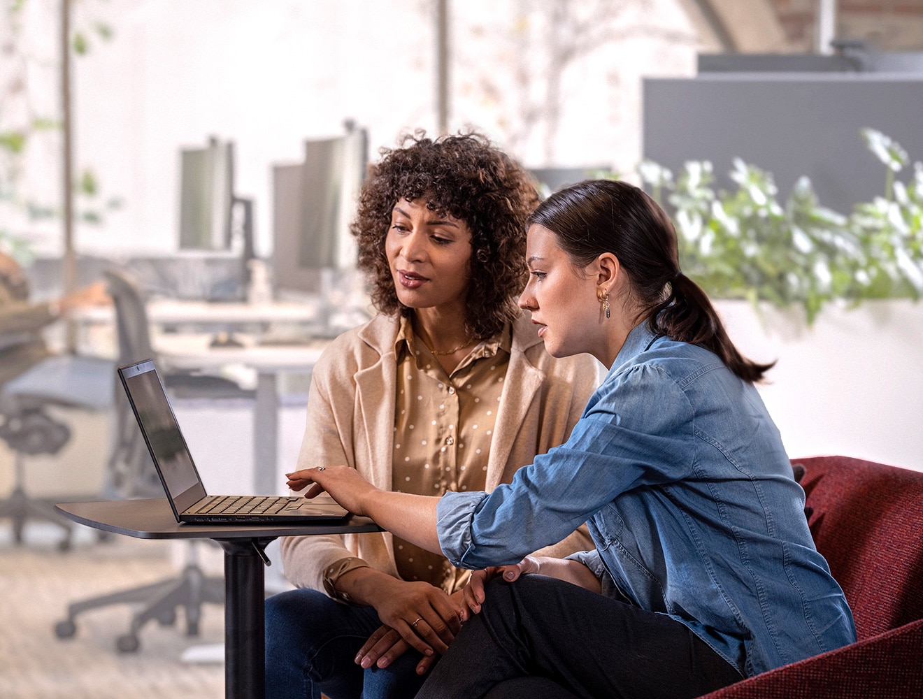 Two people working collaboratively on a design file on a laptop