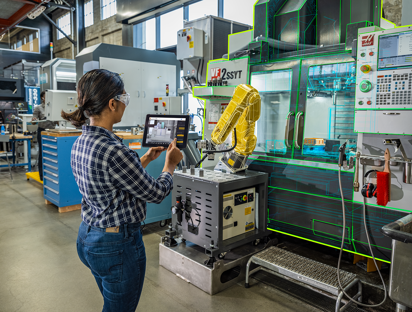 Manufacturing engineer adjusting details on tablet in front of CNC machine