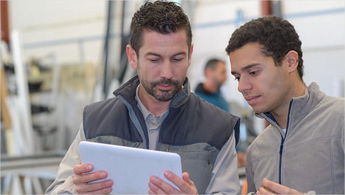 Engineers analyzing manufacturing data on tablet.