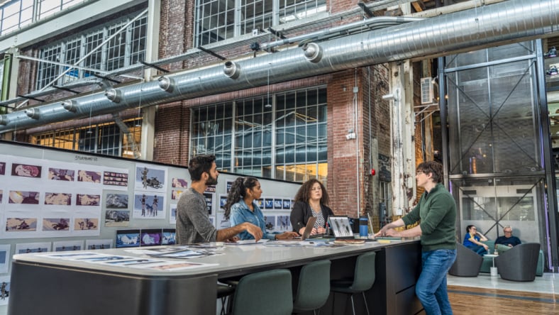 4 people standing around a table in an office talking