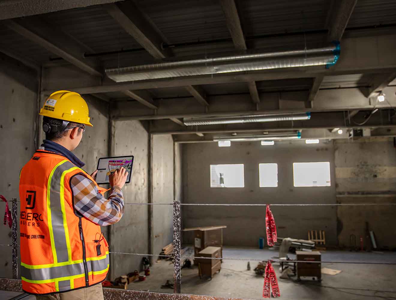 Construction worker using tablet on indoor job site.