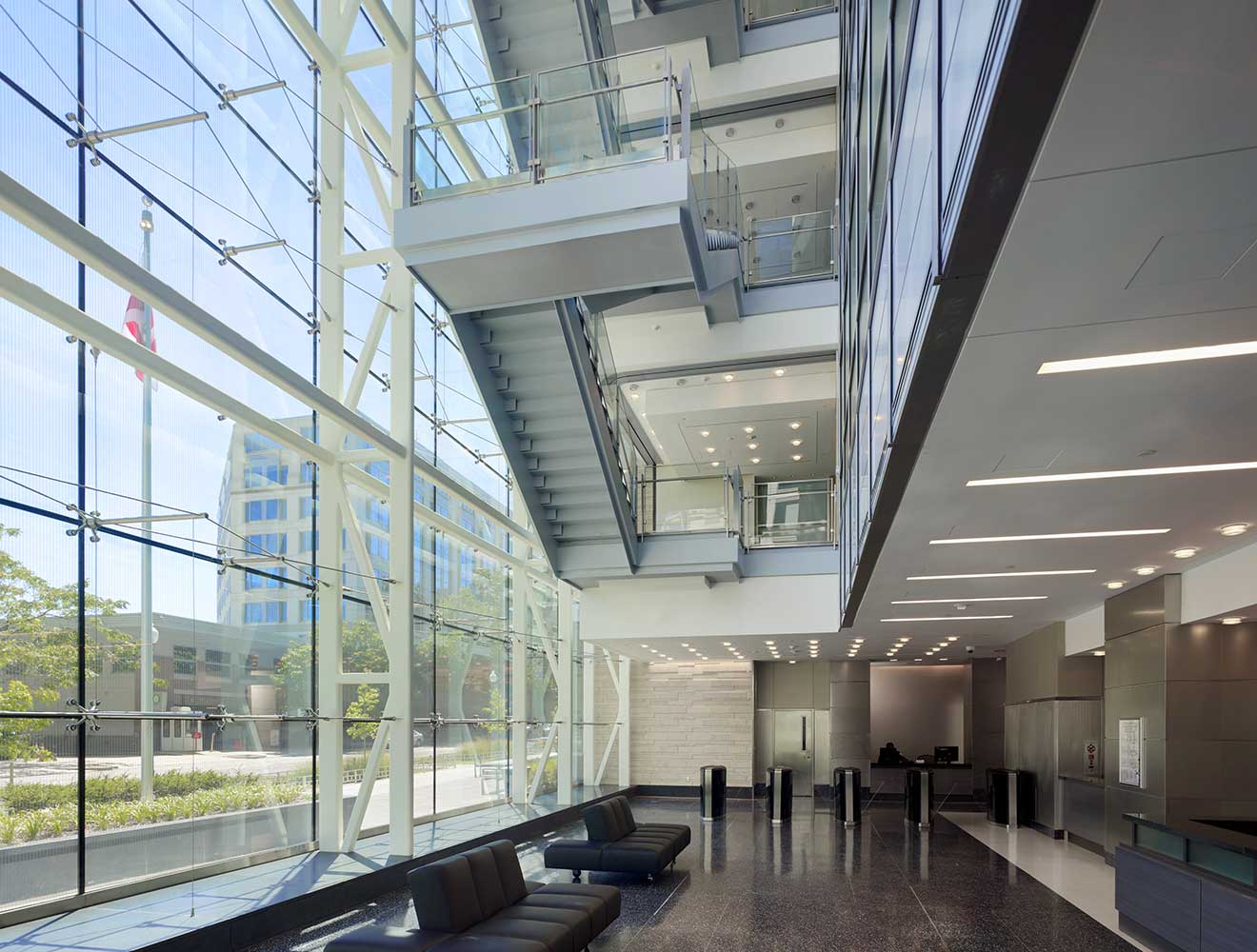 Modern office lobby with glass walls and open staircase.