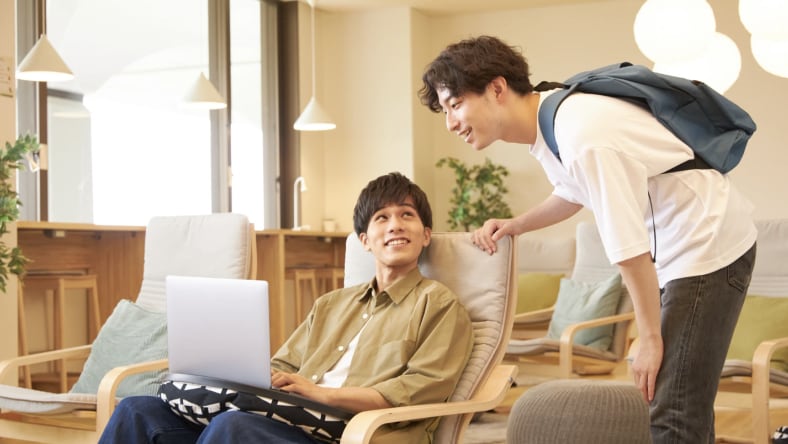 Teacher and student smiling in front of a computer