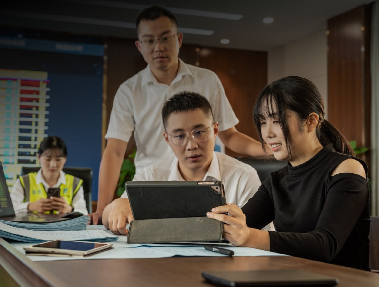 A man and woman are engaged in conversation while looking at a tablet computer together.