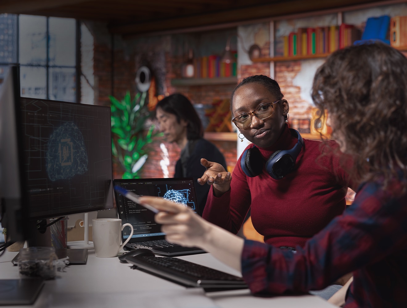  Two women work side by side on a computer, discussing and contributing to their project.